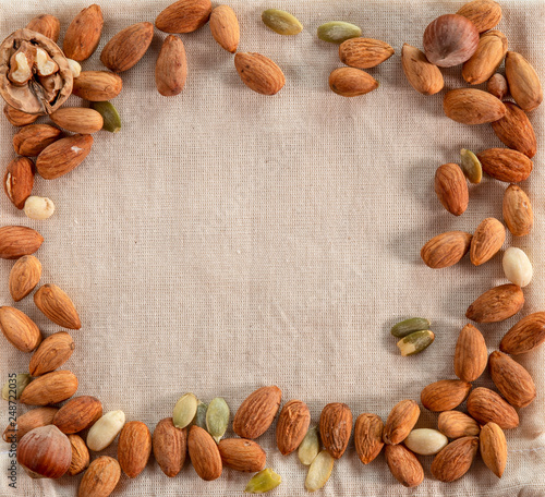 Almonds, walnuts, hazelnut and pumpkin seeds on the burlap background. Top view.