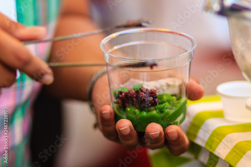 Close up Cendol vendor selling his new cendol formula at night market. The main ingredients are coconut milk, green rice flour jelly with pandan leaves juice, palm sugar, taro and purple sticky rice. photo