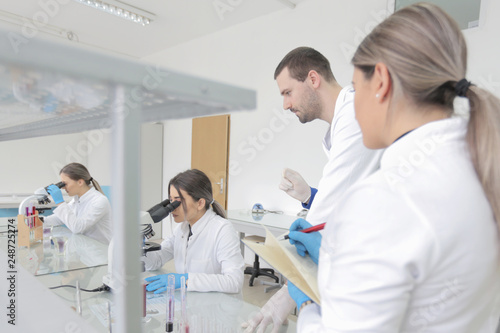 Group of young Laboratory scientists working at lab with test tubes and microscope, test or research in clinical laboratory.Science, chemistry, biology, medicine and people concept.