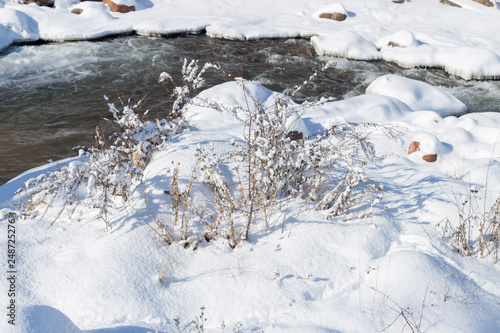 smooth movement of wild water in a river in winter with snow and ice on rocks and stones in beautiful nature