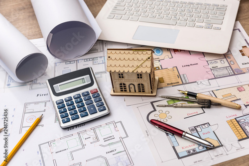 House model on architect drawing with laptop and calculator