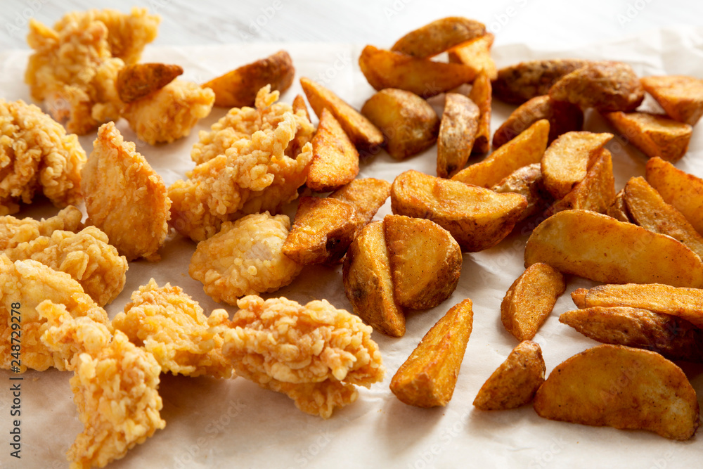 Side view, fried potato wedges and chicken bites. Close-up. Side view, fried potato wedges and chicken bites. Close-up.