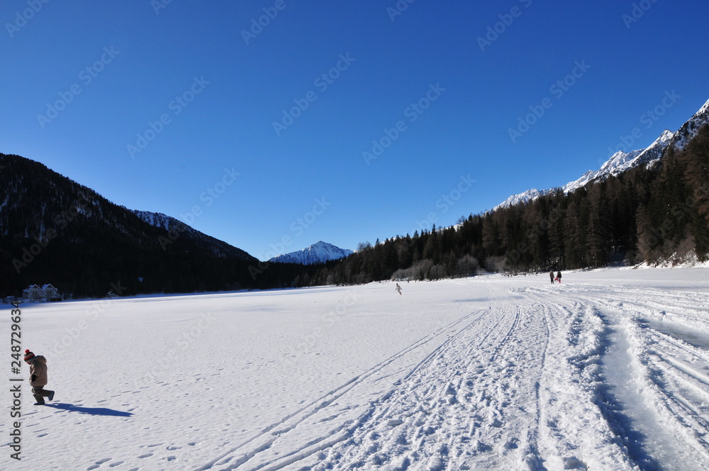snow-covered landscape with blue sky, mountains and cross-country trails