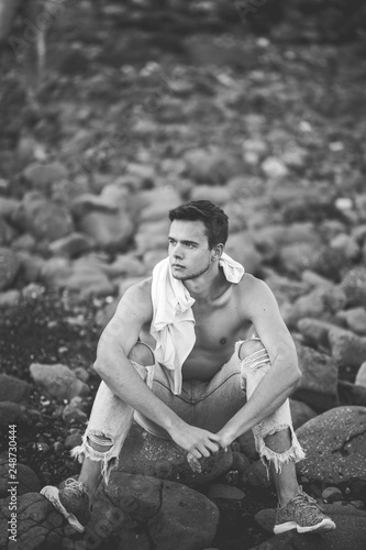 photography of young man on the stone beach