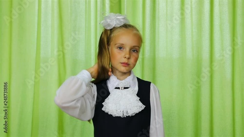 schoolgirl straightens her blond hair with her right hand.