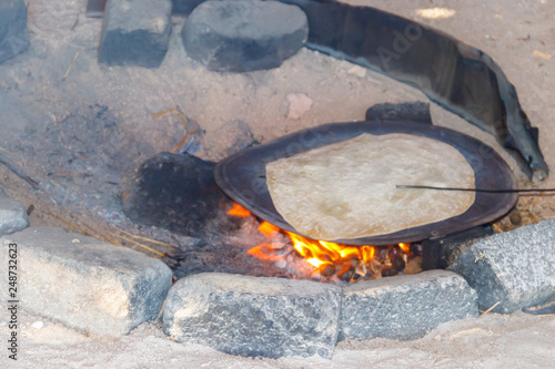 Traditional arabic pita bread cooking on fire in bedouin dwelling