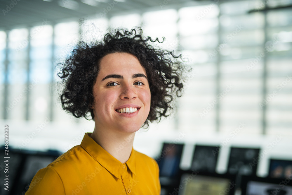Portrait of a young student or businesswoman in room in a library or office. Portrait of a young student or businesswoman in room in a library or office.