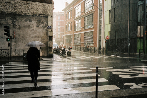 Woman with umbrella walking in the rainy street in Paris