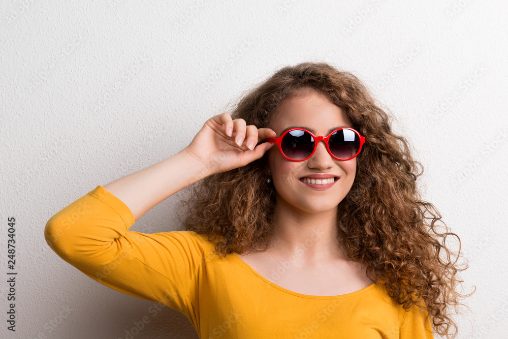 A young beautiful cheerful woman with red sunglasses in studio. A young beautiful cheerful woman with red sunglasses in studio.