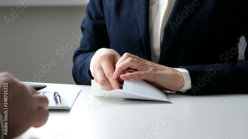 A woman giving bribe money in a white envelope to another businessman in a corruption scam, close up