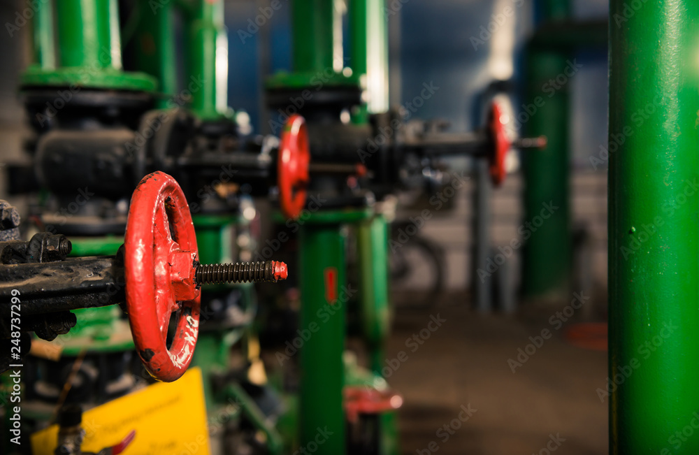 water supply pipes with red valves in technical room