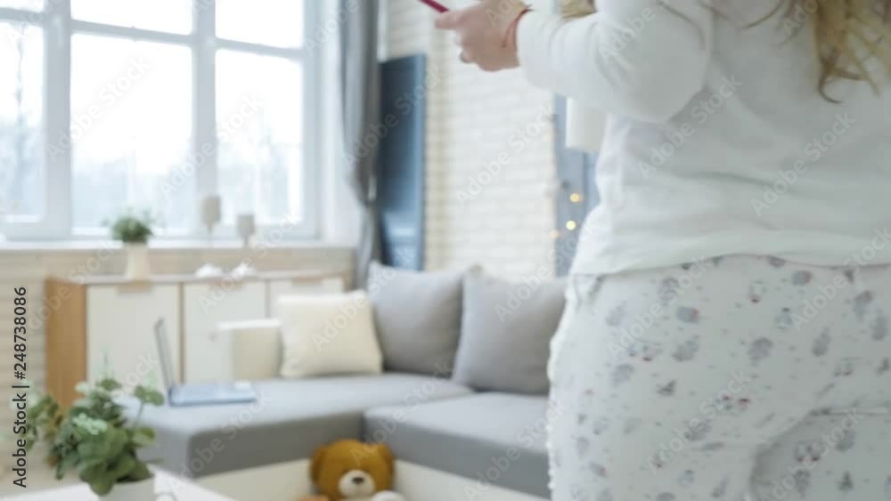 Young blonde puts the mug on the table and lay down on the sofa with a smartphone in hand Young blonde puts the mug on the table and lay down on the sofa with a smartphone in hand