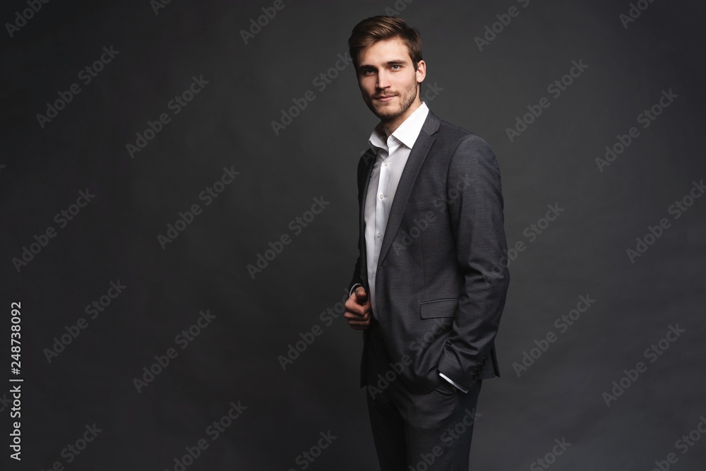 Portrait of a handsome young businessman dressed in suit isolated over gray background. Portrait of a handsome young businessman dressed in suit isolated over gray background.