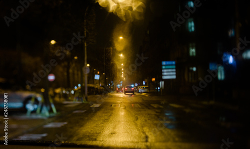 Driver pov personal perspective at the two driving car in the front road on a French street in the night - tilt-shift lens with shallow focus