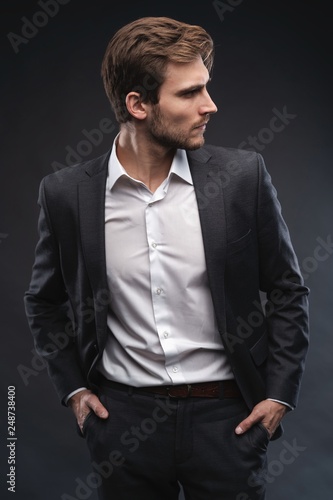 Portrait of a handsome young businessman dressed in suit isolated over gray background.