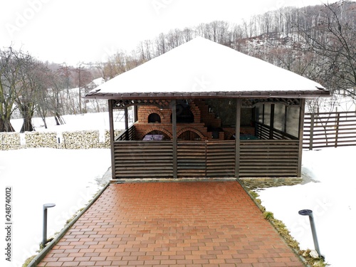 Wooden pavilion for barbecue in the garden - wintertime photo