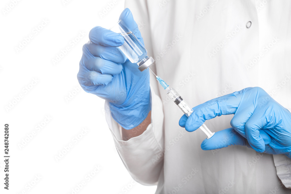 Doctor holding a syringe and a bottle with an injection solution Doctor holding a syringe and a bottle with an injection solution