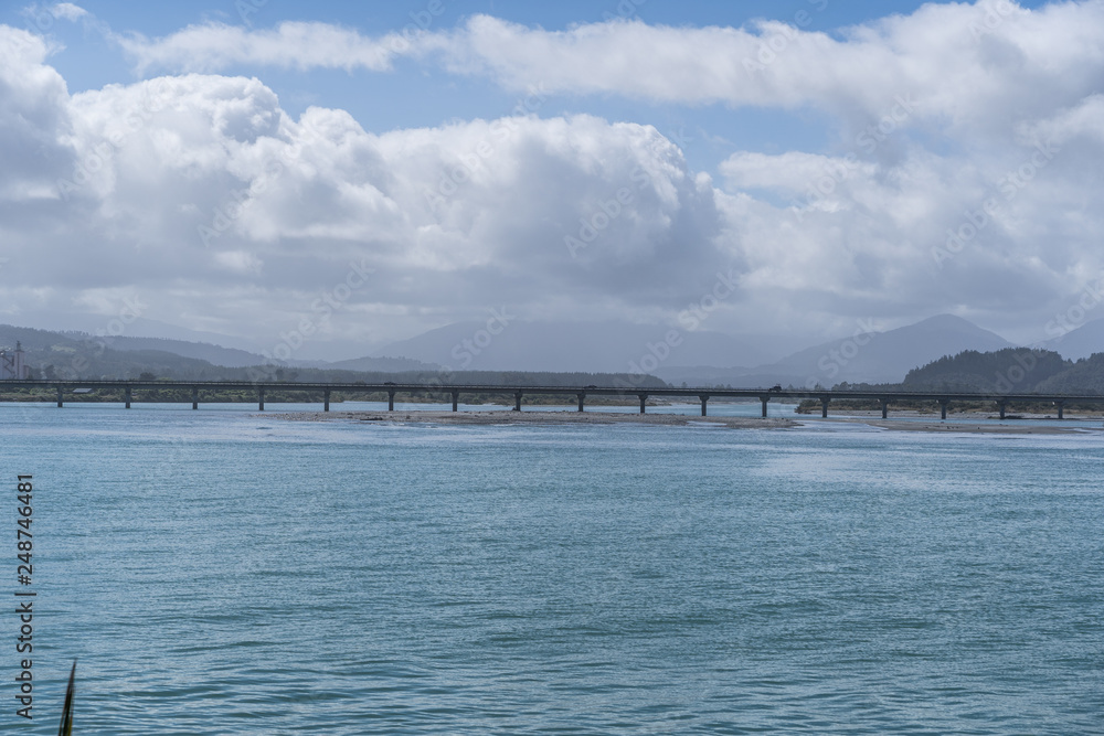 long bridge in New Zealand with blue sky background und the ocean in the foreground