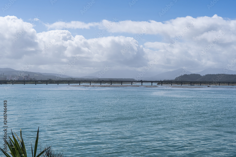 long bridge in New Zlong bridge in New Zealand with blue sky background und the ocean in the foregroundealand with blue sky background und the ocean in the foreground