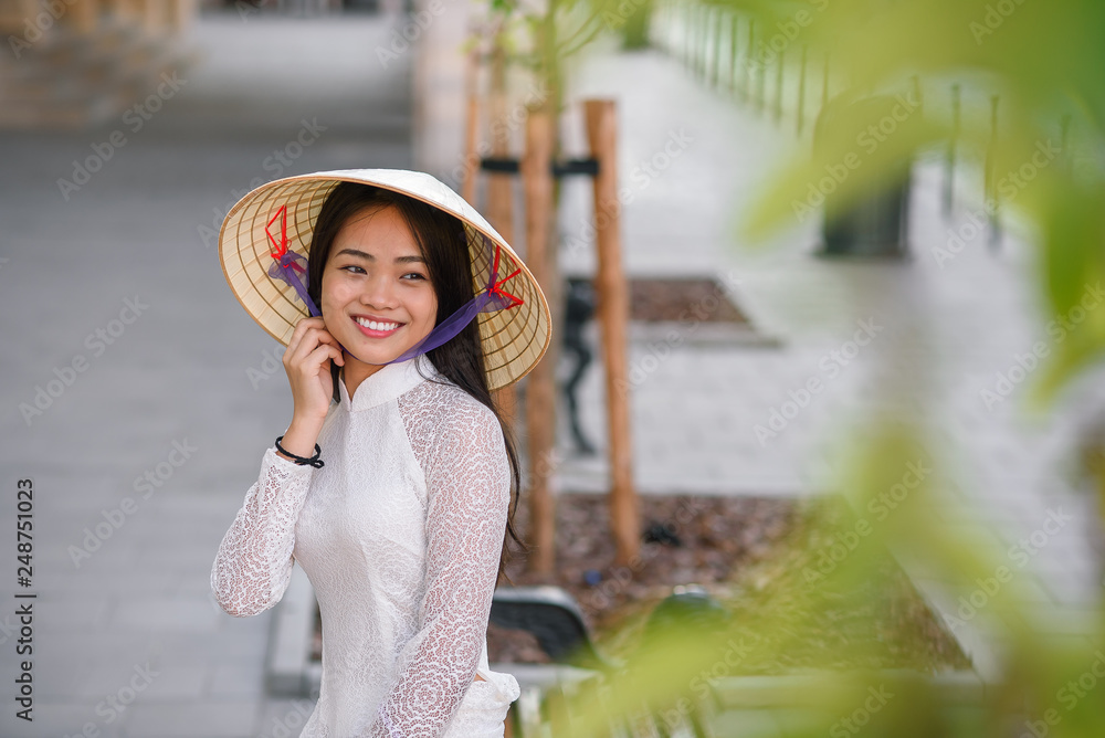 Close up portrait of pretty asian girl dressed in Ao Dai dress wearing vietnamese conical hat.