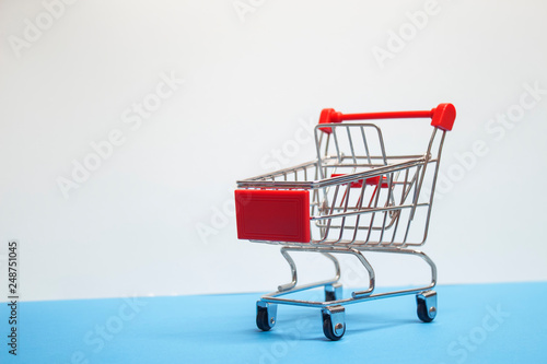 Sale concept. Supermarket trolley on a white wall background.