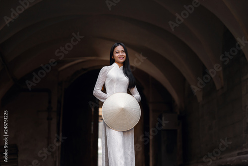 Beautiful happy asian girl dressed in national traditional Ao Dai dress with vietnamese conical hat Non La, Leaf Hat.