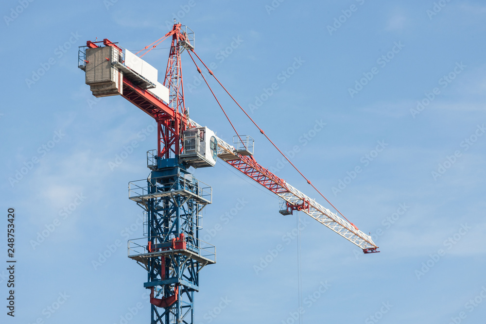 The top of the tower crane against the blue sky. Sunny day