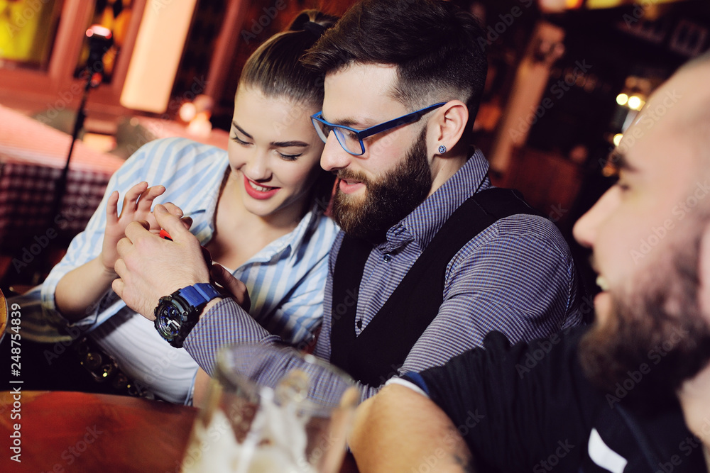 Φωτογραφία a group of friends - young guys and girls drinking beer, talking and smiling at