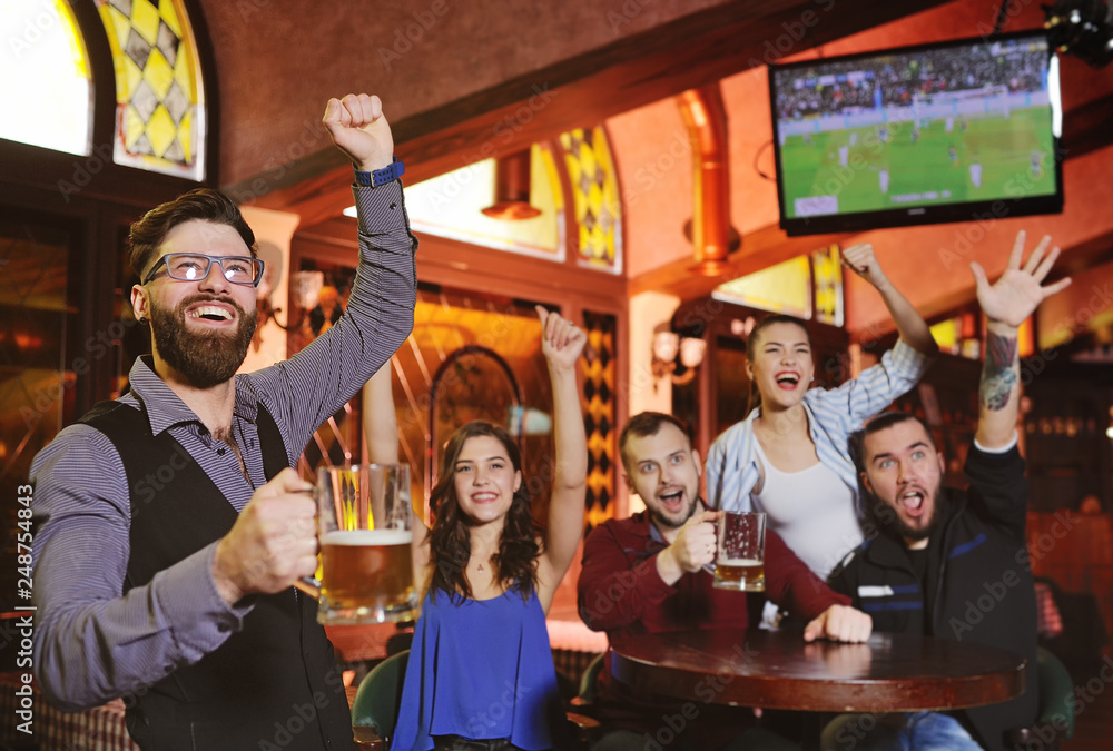 Φωτογραφία group or company of friends - young guys and girls holding glasses of beer, watc