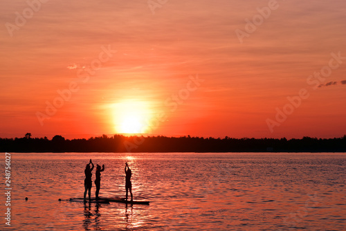 Girls doing yoga exercise on sup board with the sunrise in Gili Trawangan Island, Indonesia