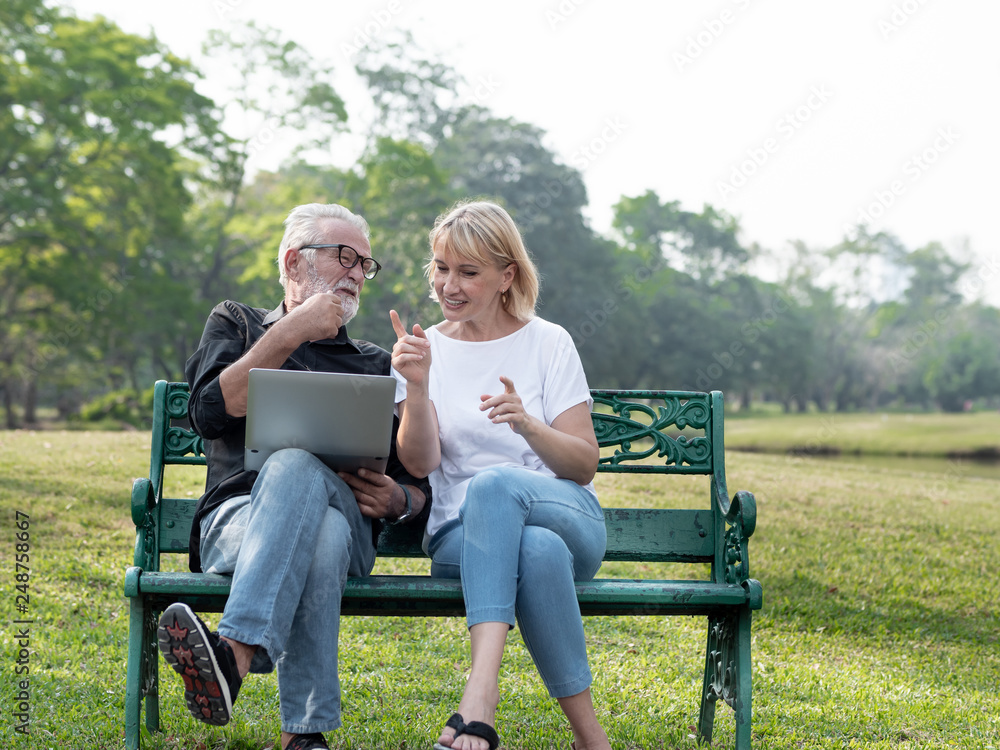 Senior man and woman couple connected on laptop computer in a park on a sunny day. relax in the forest spring summer time. free time, lifestyle retirement grandparents concept. Senior man and woman couple connected on laptop computer in a park on a sunny day. relax in the forest spring summer time. free time, lifestyle retirement grandparents concept.