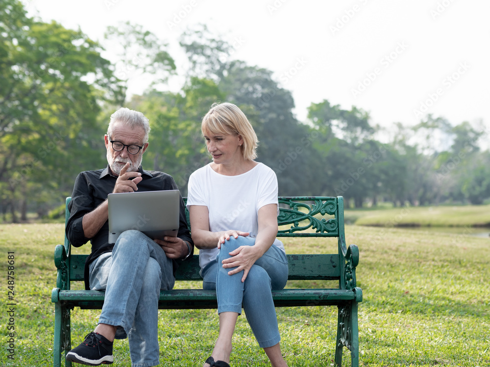 Senior man and woman couple connected on laptop computer in a park on a sunny day. relax in the forest spring summer time. free time, lifestyle retirement grandparents concept. Senior man and woman couple connected on laptop computer in a park on a sunny day. relax in the forest spring summer time. free time, lifestyle retirement grandparents concept.
