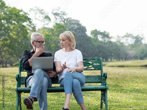 Senior man and woman couple connected on laptop computer in a park on a sunny day. relax in the forest spring summer time. free time, lifestyle retirement grandparents concept. © xreflex