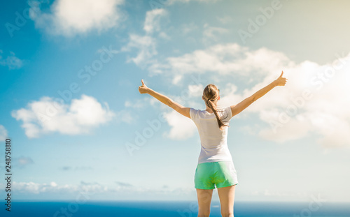 Winning, success , and life goals concept. Young woman with arms in the air giving thumbs up.