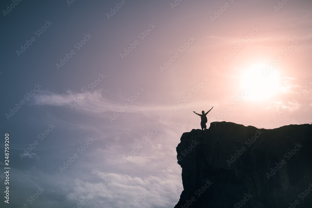 silhouette of motivated man on top of mountain