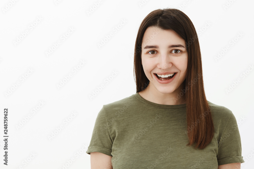 Carefree happy and optimistic young brunette in 20s wearing olive t-shirt smiling broadly with amazement and joy, having fun, feeling upbeat and entertained as standing amused over gray background Carefree happy and optimistic young brunette in 20s wearing olive t-shirt smiling broadly with amazement and joy, having fun, feeling upbeat and entertained as standing amused over gray background
