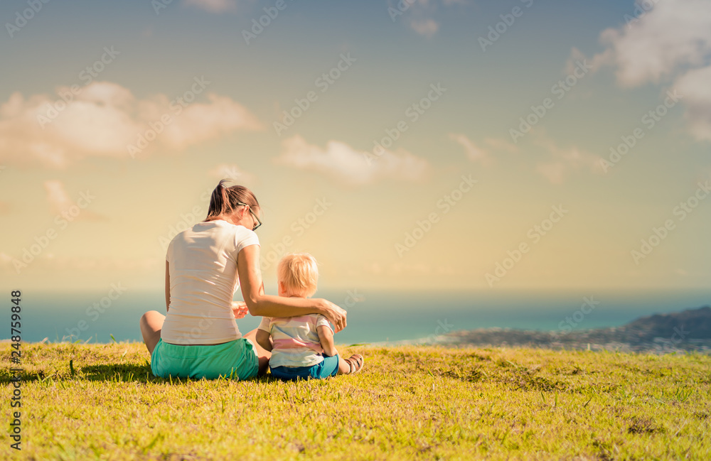 Mother and her little boy sitting together in the park 
