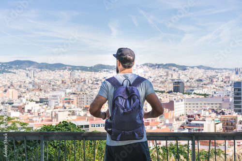 Traveler man looking on a big city, travel and active lifestyle concept.Bearded Tourist Man with backpack enjoy beautiful panoramic view of modern european city