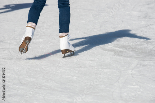 Female legs in ice skates at ice-skating rink. 