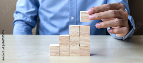 Businessman hand placing or pulling wooden block on the building. Business planning, Risk Management, Solution and strategy Concepts