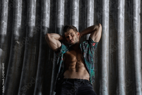 Muscular young man with beard on dark tunnel urban background. Fashion portrait of brutal strong muscle guy with modern trendy hairstyle. Model, fashion concept. Sexy naked torso, six pack abs. © KDdesignphoto