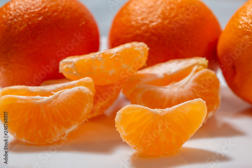 Several whole and peeled ripe tangerines on a white plate