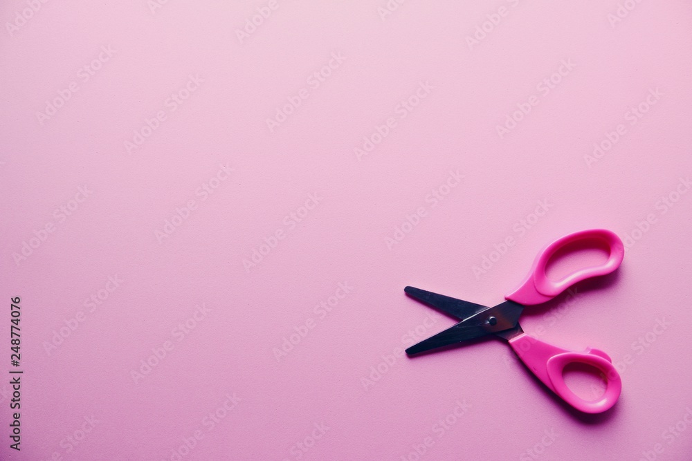 Small pink scissors on pink background close up Small pink scissors on pink background close up
