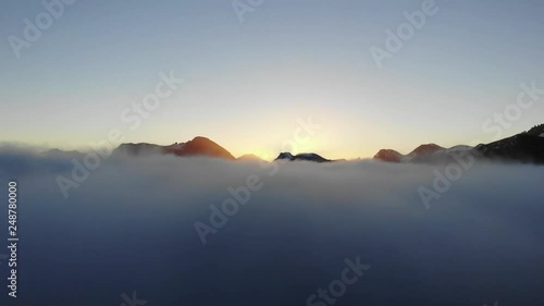 The drone shot is going from under the clouds to over the clouds. This is by hj√∏rundfjorden, Norway at sunrise, and you see the sun slowly as it comes photo