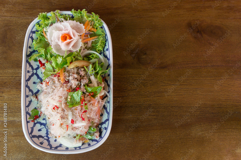 Vermicelli salad or Yum vermicelli with minced pork. Serve  in dish put on wooden table.