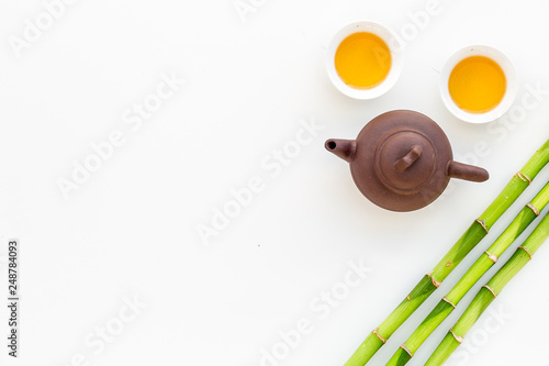 Asian tea traditions. Drink tea. Tea ceremony. Tea pot near cups of green tea and bamboo decoration on white background top view space for text