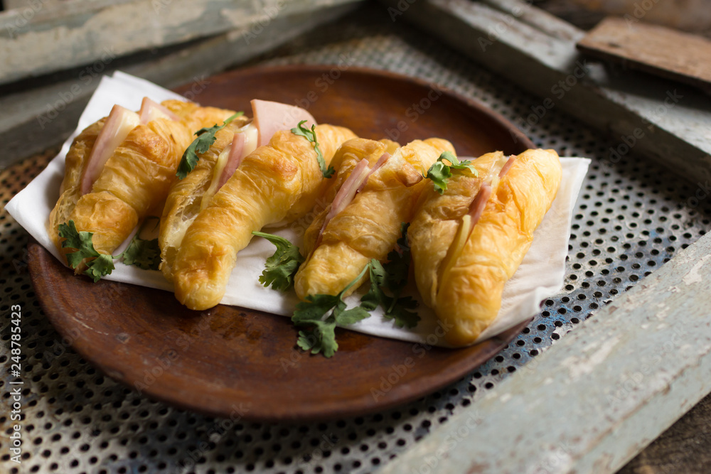 Croissant cheese in wooden dish placed on a rusty grill Croissant cheese in wooden dish placed on a rusty grill