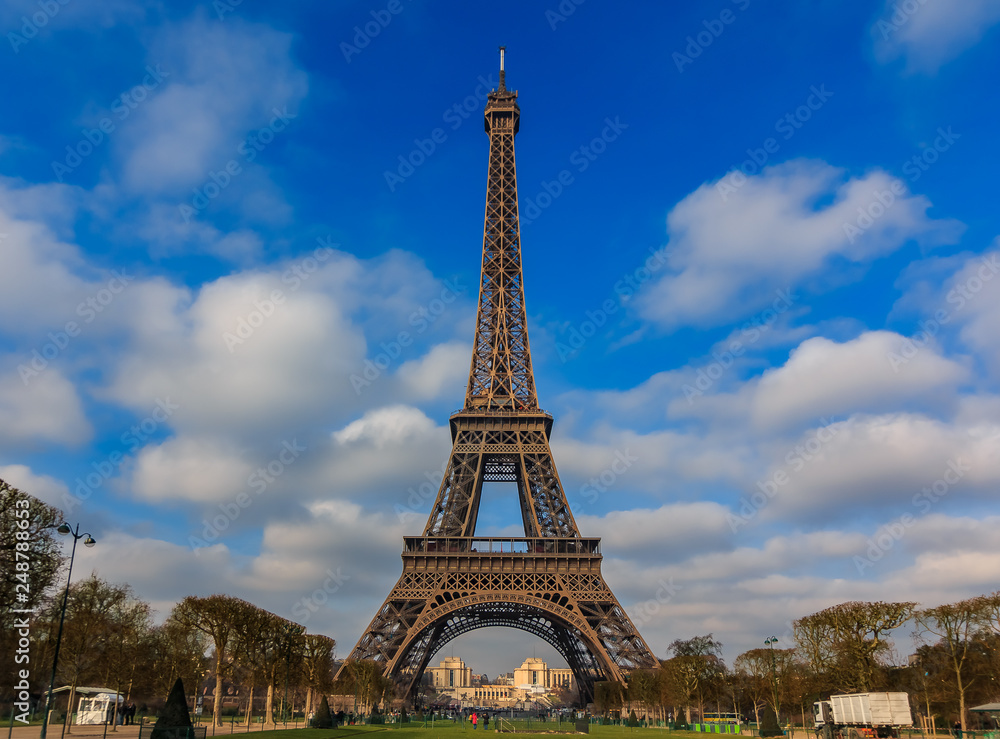 View of the Eiffel Tower or Tour Eiffel seen from Champ de Mars in Paris, France on a beautiful cloudy day