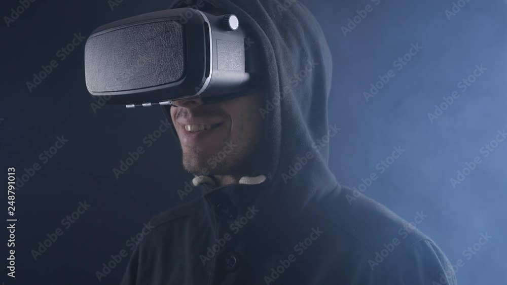 Futuristic man in hood Wearing VR Headset. Futuristic man using Virtual Reality Glasses in a dark smoky room. Futuristic man in hood Wearing VR Headset. Futuristic man using Virtual Reality Glasses in a dark smoky room.
