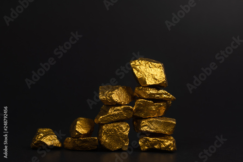 A pile of gold nuggets or gold ore on black background, precious stone or lump of golden stone, financial and business concept. photo